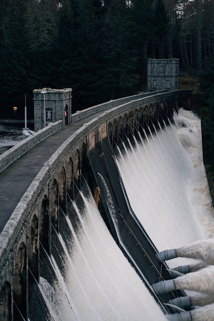 Majestic dam in the Scottish Highlands releasing water with lush forest backdrop.